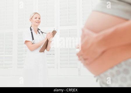 Medico a parlare con una donna in stato di gravidanza Foto Stock