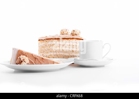 Crema nocciola torta con una tazza di caffè su sfondo bianco Foto Stock