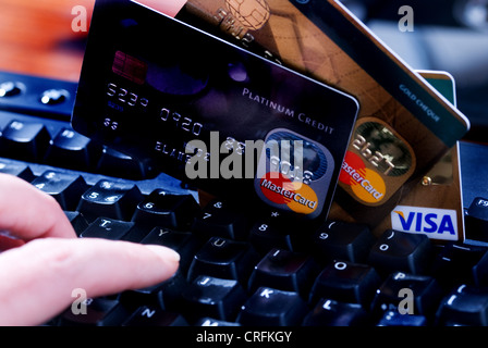 Tastiera del computer con una mano e le carte di credito, sulle vendite di linea. Foto Stock