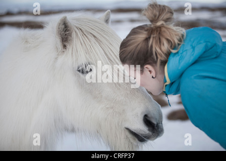Donna kissing cavallo bianco nella neve Foto Stock