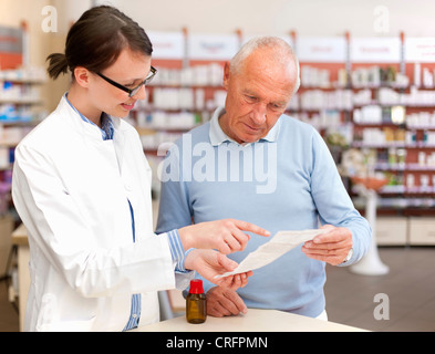 Il farmacista di parlare al paziente in store Foto Stock