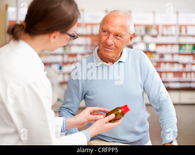 Il farmacista di parlare al paziente in store Foto Stock