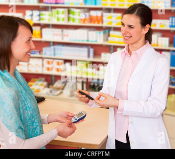 Il farmacista di parlare al paziente in store Foto Stock