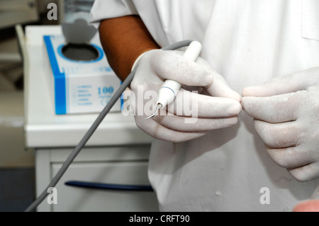 Un dentista tenendo un raschiatore dentali utilizzati per la rimozione di detriti dai denti e gengive Foto Stock