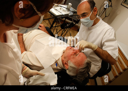 Dentista di esaminare la condizione dei suoi pazienti a denti e gengive. Foto Stock