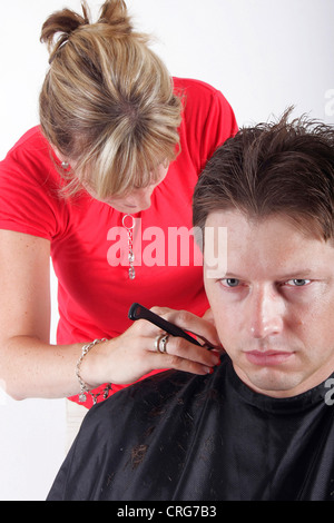 Uomo al parrucchiere. La femmina parrucchiere utilizza un rasoio Foto Stock