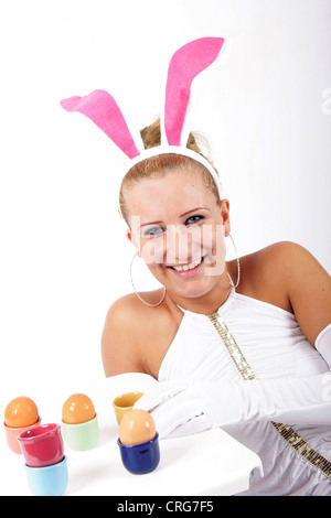 Giovane donna bionda con rosa orecchie di coniglio e le uova di Pasqua Foto Stock