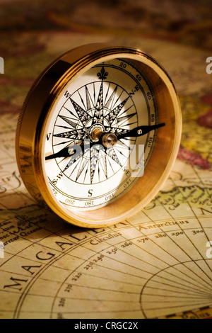 Un oro antico compass impostato su di un sedicesimo secolo mappa del mondo Foto Stock