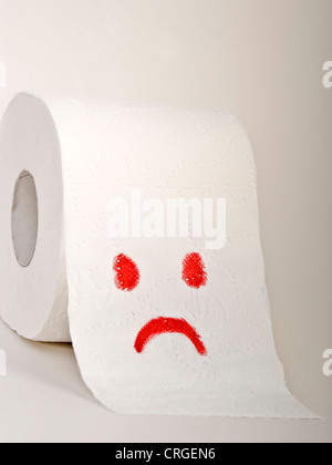 Immagine simbolica per cattiva digestione: loo roll con bad smiley Foto Stock