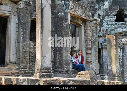 Tempio Khmer area di Angkor Wat, due turisti in appoggio all'ombra del tempio Bayon, Cambogia Foto Stock