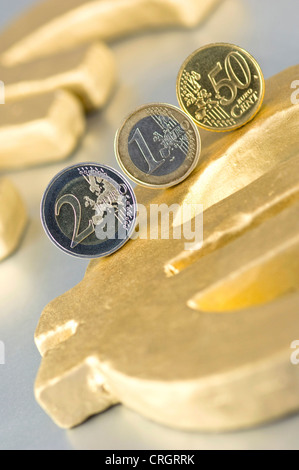 Tre monete in euro su un golden Euro segno Foto Stock