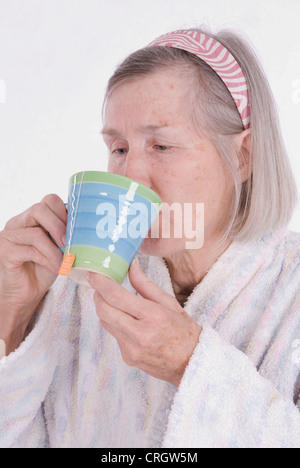Anziani malati donna in accappatoio bevendo una tazza di tè Foto Stock