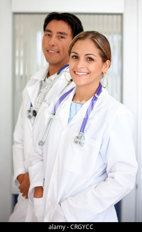 Giovani donne medico con pelo bianco e stetoscopio in piedi di fronte a un collega di sesso maschile, sorridente Foto Stock