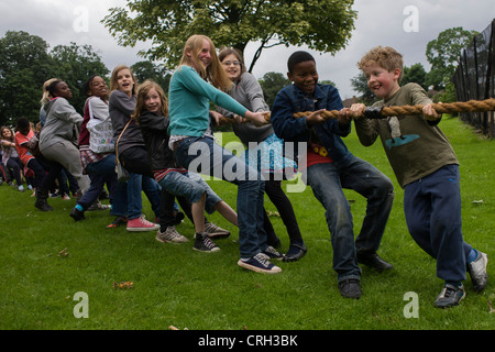 Bambini locali heave-ho su una corda di grandi dimensioni per il migliore dei tre tug o i giochi di guerra durante una comunità park festival. Foto Stock