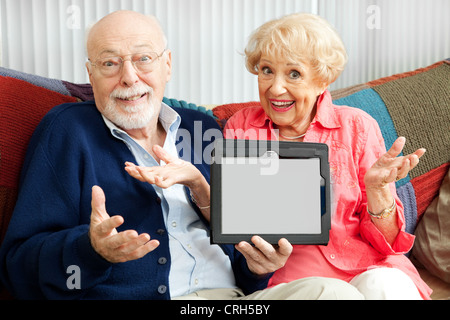 Confuso coppia senior tenendo il loro nuovo tablet PC. Vuoto sullo schermo del computer pronto per il tuo testo. Foto Stock