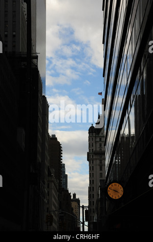 Cielo blu, il bianco delle nuvole ombra scura " urbano alley' orologio sul marciapiede ritratto, East 58th Street, a bandiera americana Hotel Plaza di New York Foto Stock