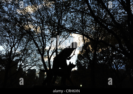 Alla luce della sera vista silhouette cacciatore indiano scultura in piedi di fronte ad autunno alberi, Central Park South, New York Foto Stock