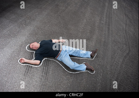 Un uomo morto in strada delineata con chalk dalla scena del crimine gli investigatori. Foto Stock