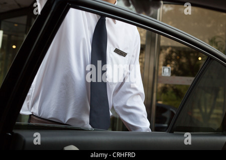 Hotel portantino apertura porta auto per il trasporto di passeggeri a Pechino in Cina. Foto Stock