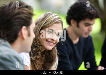 Giovani carino donna seduta tra due uomini, sorridente Foto Stock