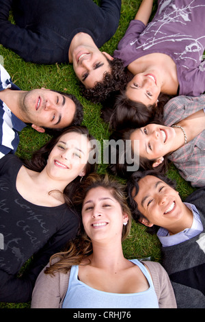 Gruppo di amici che giace testa a testa sul prato Foto Stock