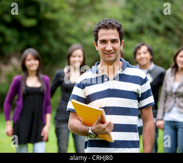 Studente di college sorridente all aperto con i suoi amici dietro di lui Foto Stock