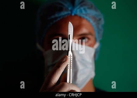 Chirurgo tenendo un bisturi verso la telecamera. Foto Stock