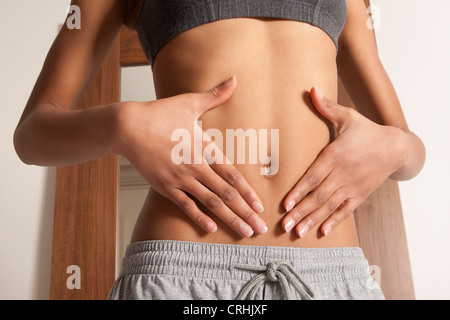 Womans mani coppettazione la sua bellybutton Foto Stock