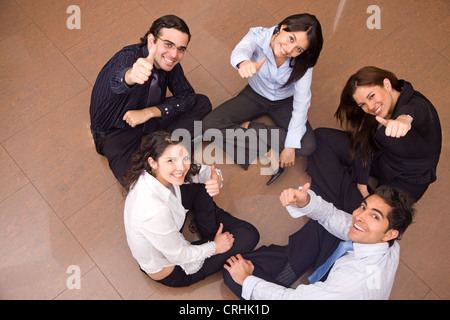 La gente di affari in un gruppo con il pollice in su in un ufficio Foto Stock