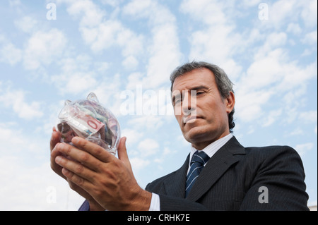 Uomo maturo azienda trasparente salvadanaio riempito con Euro Foto Stock