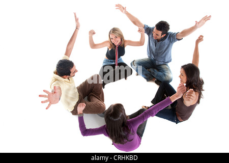 Gruppo informale di giovani seduti in cerchio sul pavimento, il tifo con le braccia tese Foto Stock