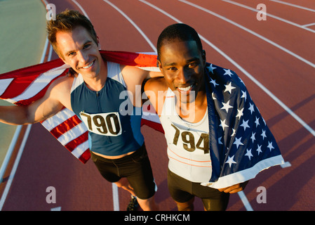 Esecuzione di compagni di squadra mantenendo la bandiera americana dopo gara Foto Stock