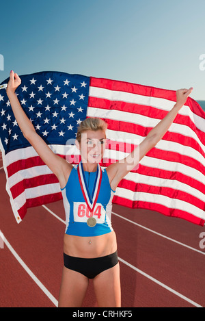 Femmina vincitore della medaglia mantenendo la bandiera americana in segno di vittoria Foto Stock