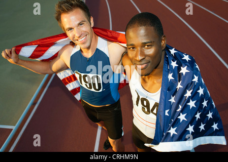 Esecuzione di compagni di squadra mantenendo la bandiera americana dopo gara Foto Stock