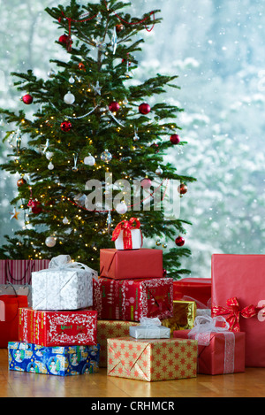 Festively avvolto doni impilati nella parte anteriore dell albero di Natale Foto Stock