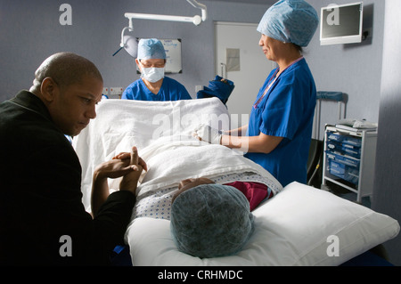 Coppia durante il trattamento di IVF con medico e infermiere in background Foto Stock