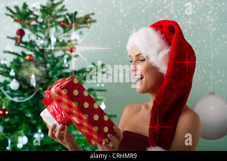 Donna che indossa Santa hat, guardando i regali di Natale Foto Stock