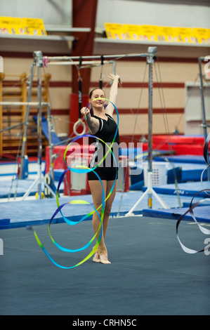 Ragazza adolescente ginnasta praticare ginnastica ritmica, fa roteare il nastro Foto Stock