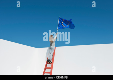 Imprenditrice in piedi alla parte superiore della scaletta, tenendo bandiera dell'Unione europea Foto Stock