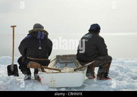 Due saldatori Inuit seduti a bordo di ghiaccio sulla loro barca a remi e si affacciano sul mare aperto, Groenlandia, Ostgroenland, Tunu, Kalaallit Nunaat, Scoresbysund, Kangertittivag, Kap Tobin, Ittoqqortoormiit Foto Stock