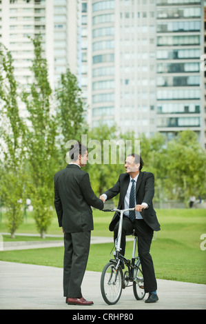 Saluto gli imprenditori a vicenda con handshake, un uomo in bicicletta Foto Stock