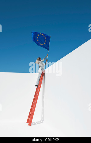 Imprenditrice in piedi alla parte superiore della scaletta, tenendo bandiera dell'Unione europea Foto Stock