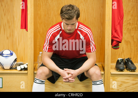 Soccer giocatore seduto da solo in spogliatoio Foto Stock