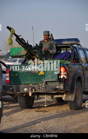 Un lapidato poliziotto afghano pone con una massa alla pistola ad aria montato sul retro di un pickup, registrati POO. Foto Stock