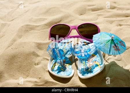 Occhiali da sole e sandali in vacanza sulla spiaggia di concetto di segno Foto Stock