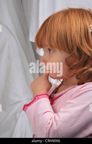 Poco i Capelli rossi ragazza in pigiama cercando sognanti Foto Stock