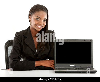 Sorridente giovane donna d'affari seduti ad una scrivania con un notebook girato per la fotocamera Foto Stock