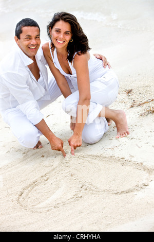 Felice Coppia sorridente in spiaggia, il disegno di un cuore sulla sabbia Foto Stock