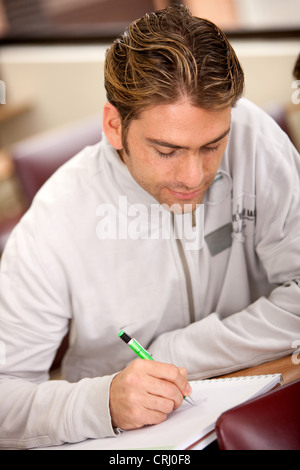 Studente universitario rendendo note su un raccoglitore ad anelli Foto Stock