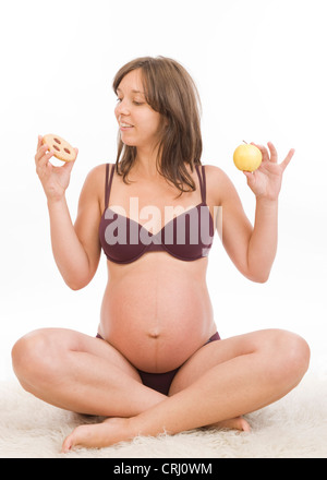 Donna incinta con cookie e Apple in mani Foto Stock